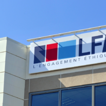 Enseigne du logo LFB « L'engagement éthique » installée en hauteur sur la façade d'un bâtiment, sous un ciel bleu dégagé.