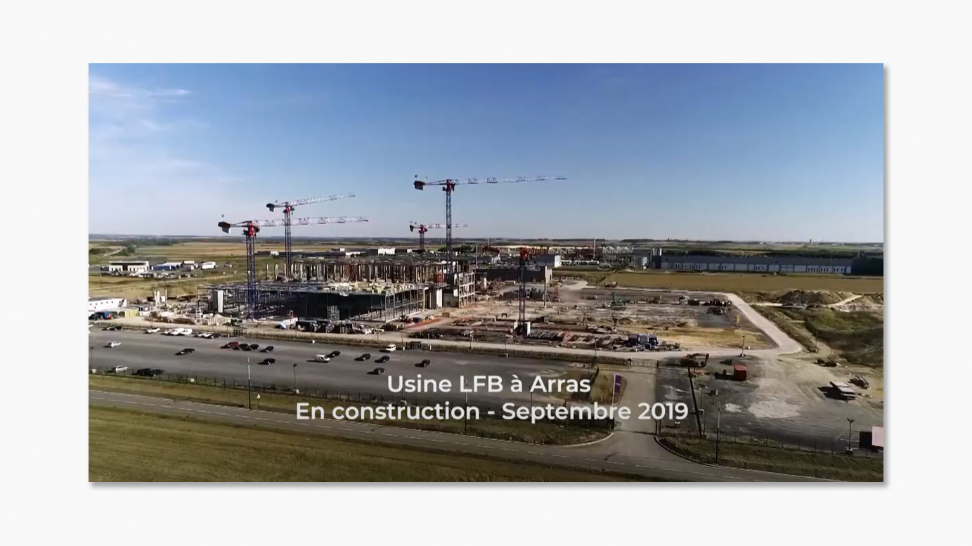 Vue aérienne du chantier de l'usine LFB à Arras en septembre 2019, avec plusieurs grues et bâtiments en construction.