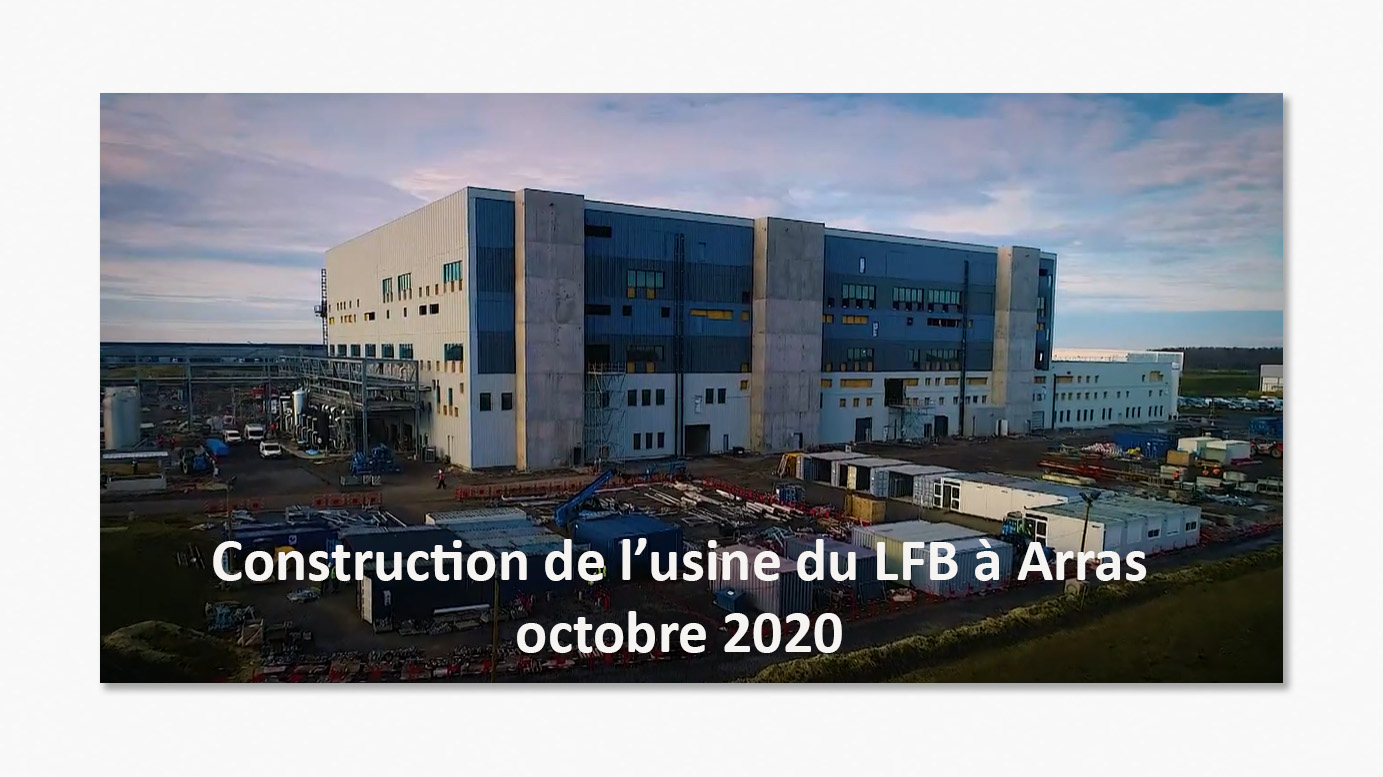 Vue de l'usine LFB à Arras en construction, octobre 2020, avec des bâtiments gris et bleus et des conteneurs de chantier.