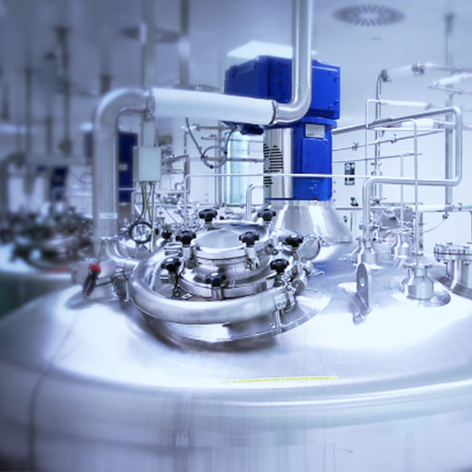 Installation industrielle avec cuve et tuyauteries dans un environnement de production pharmaceutique.
