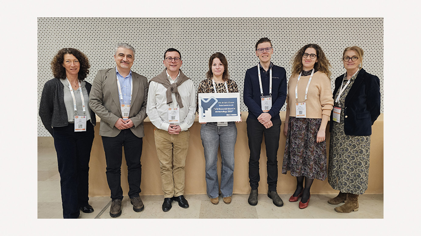 Photo de groupe de sept personnes portant des badges de conférence, posant côte à côte devant un mur. Au centre, une femme tient un panneau : « CHU de Saint-Étienne, équipe lauréate du prix "LFB Research Grant in Immunology 2025" ».